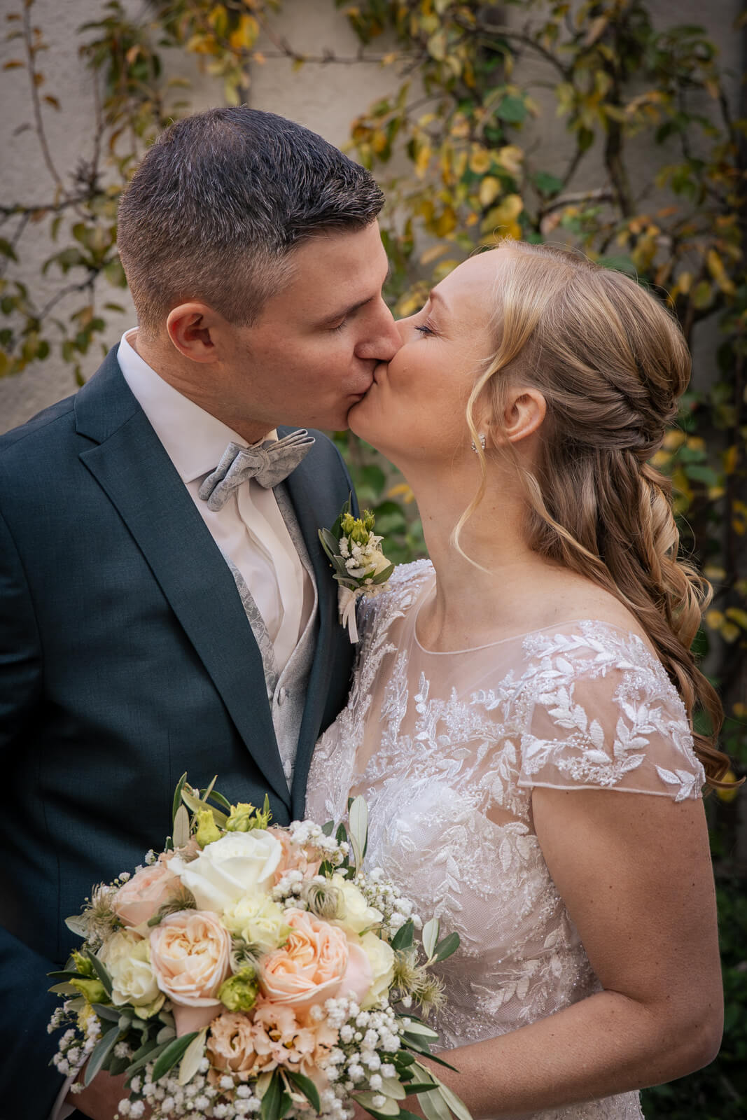 Hochzeitsfotograf Kempten und Allgäu. Ein Brautpaar küsst sich innig. Im Vordergrund ist der Brautstrauß